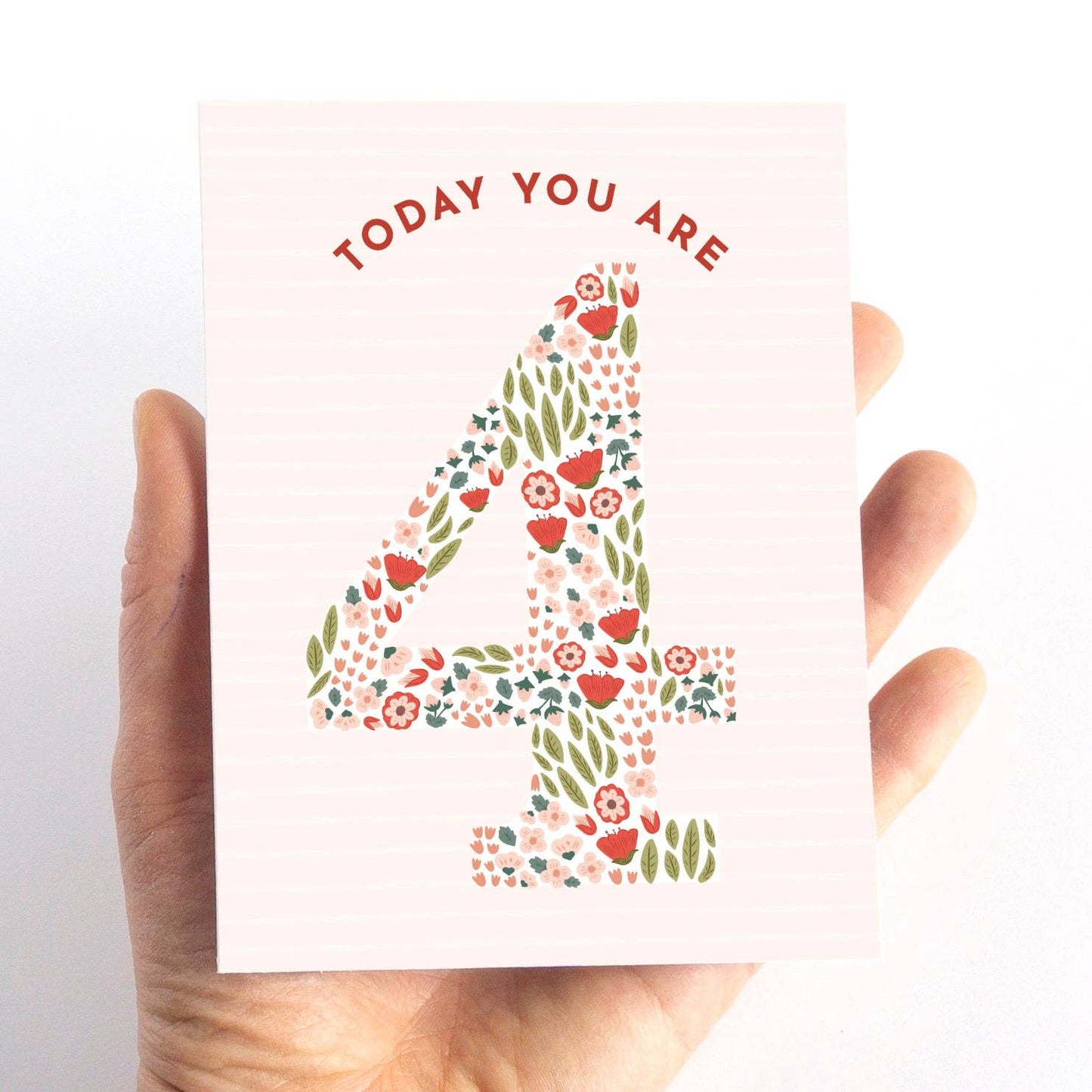 Hand holding a card with floral number '4' and text 'TODAY YOU ARE 4' on a white background