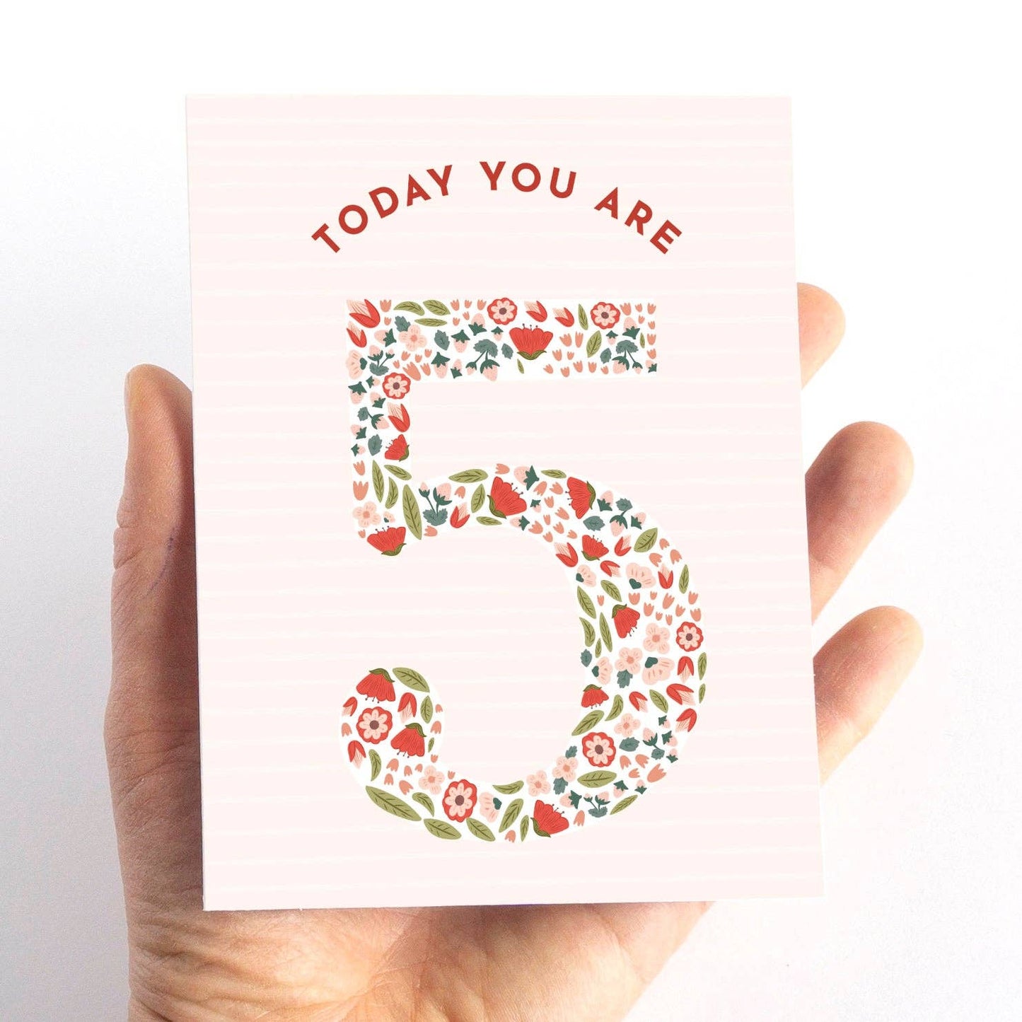 Hand holding a card with floral number '5' and text 'TODAY YOU ARE 5' on a white background