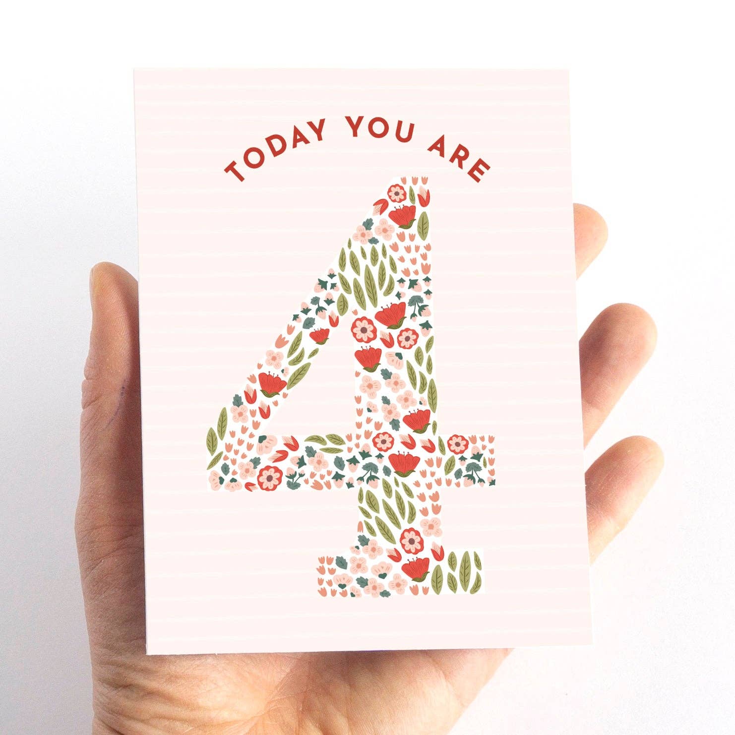 Hand holding a card with floral number '4' and text 'TODAY YOU ARE 4' on a white background