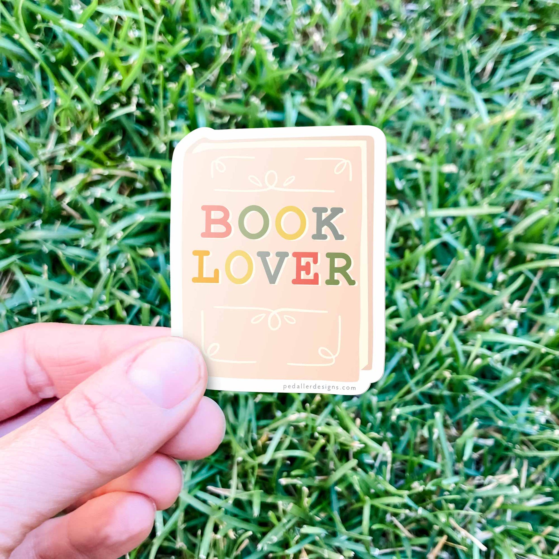 Card with 'Book Lover' text held over grass