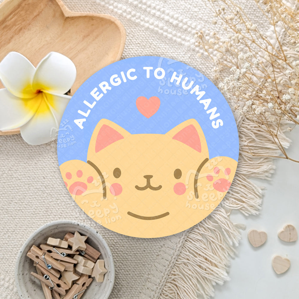 Round sticker with a cat design and text 'Allergic to Humans' on a decorative background.