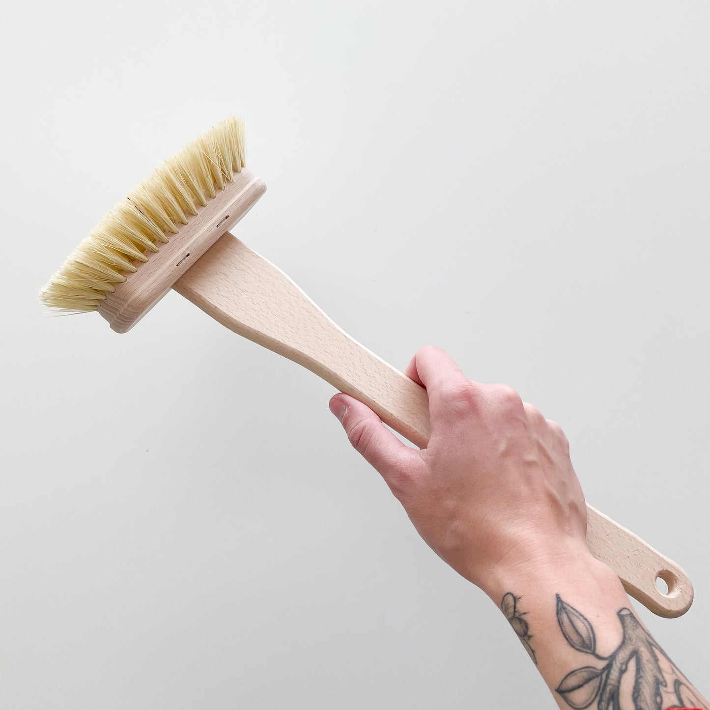 a hand holding a long bath cleaning brush