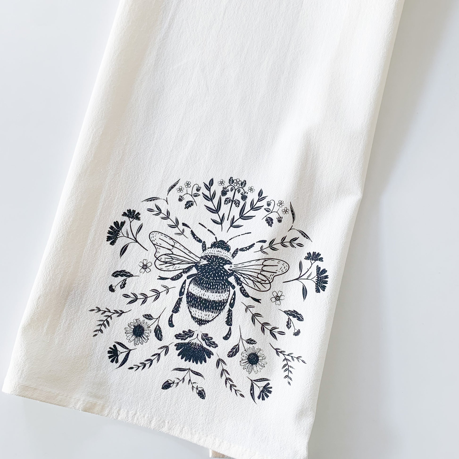 Close up of the bee and floral detail on a cotton tea towel.  - Kinsfolk Shop